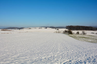 Snow landscape with fields and fog in the valley and with blue sky in spessart, bavaria, germany