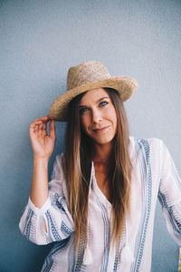 Woman wearing hat against wall