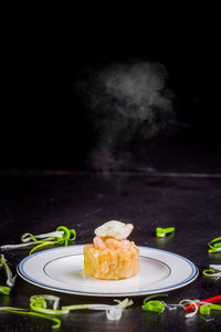 Close-up of food in plate on table against black background