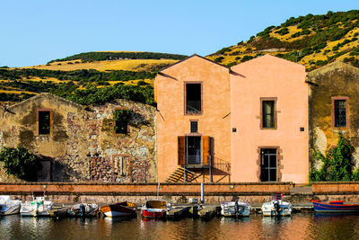 Sailboats moored on canal by buildings against clear sky