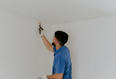 A young man paints the wall with a brush.
