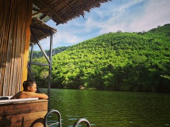 Side view of man in bathtub by lake