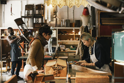 Young female entrepreneur with customer at workbench in repair shop