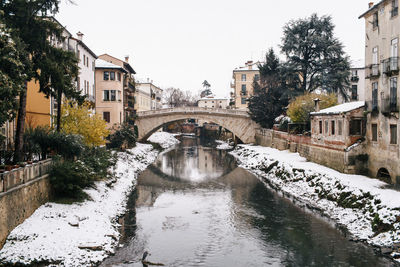 Bridge over river in city against clear sky