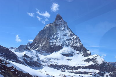 Scenic view of snowcapped mountains against blue sky