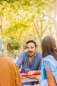 Portrait of smiling friends sitting in park