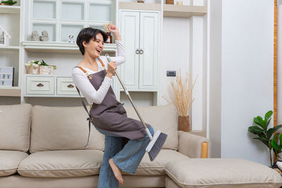 Young woman using mobile phone while sitting on sofa at home