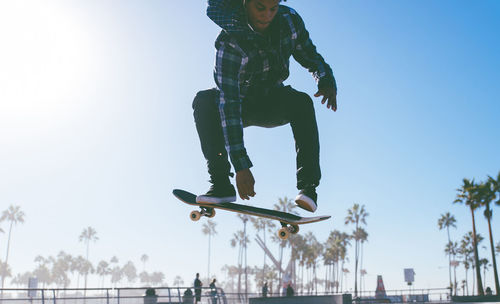 Low angle view of man jumping against sky