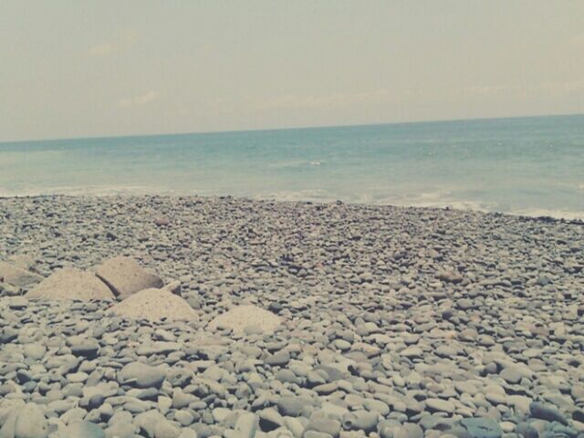 sea, horizon over water, beach, water, shore, tranquility, tranquil scene, scenics, sky, beauty in nature, nature, stone - object, pebble, rock - object, idyllic, sand, day, remote, outdoors, clear sky