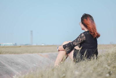 Side view of woman wearing sunglasses on field against sky