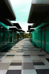 Empty road amidst buildings in city against sky