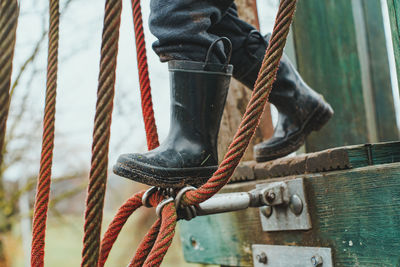 Low section of child with boots on playground rope bridge