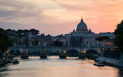 Bridge over river in city against sky during sunset