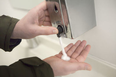 Cropped hand under soap dispenser