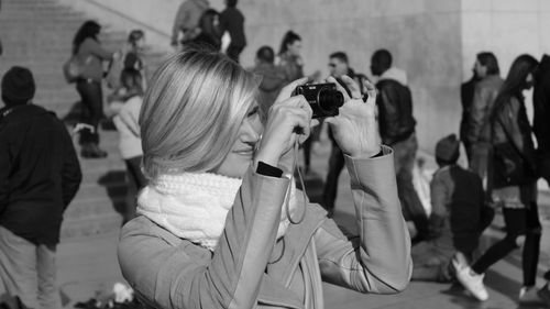 Woman photographing through camera in city