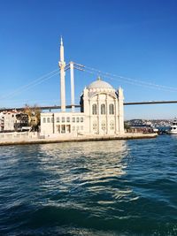 View of building by sea against blue sky