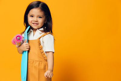 Portrait of smiling young woman against yellow background