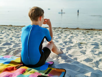 Rear view of boy sitting on beach