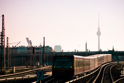 Train on tracks with fernsehturm against sky