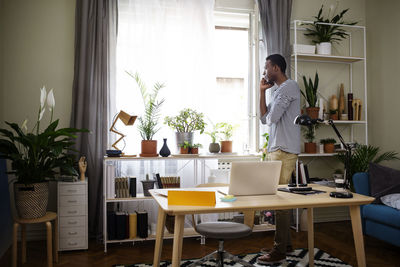Side view of man using smart phone at home office