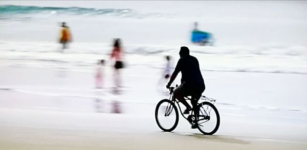 Man with bicycle on snow against sky