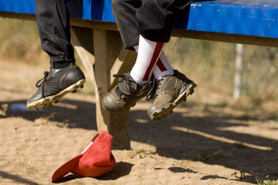 Legs of 2 boys sitting on the bench of a baseball dugout