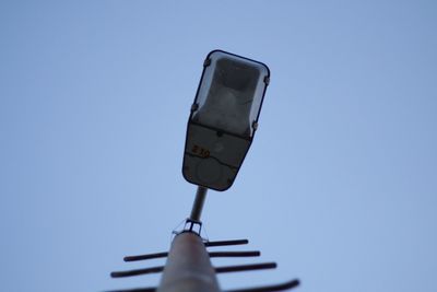 Low angle view of street light and antenna against clear blue sky