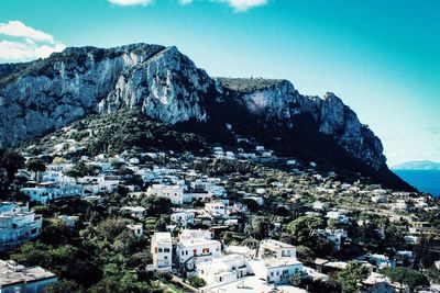 Aerial view of townscape and mountains against blue sky