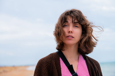 Portrait of young woman standing against sky