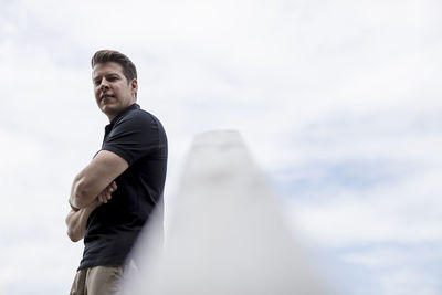 Side view of young man standing against sky