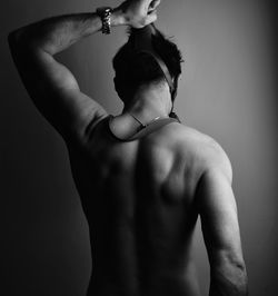 Rear view of shirtless woman standing against wall