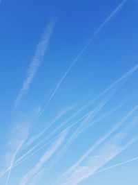 Low angle view of vapor trails against blue sky