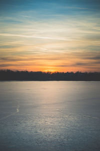 Scenic view of frozen lake against sky during sunset