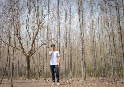 Full length of man standing by bare trees in forest