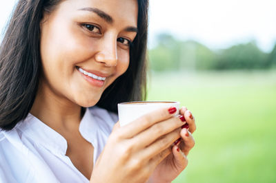 Portrait of a smiling young woman drinking coffee