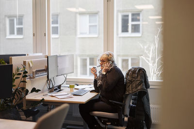 Woman using cell phone in office