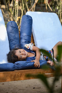 Portrait of girl lying on sofa in yard