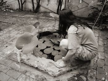 Young woman crouching by pond