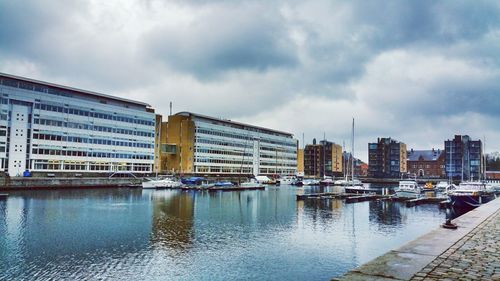 Buildings by river against sky in city