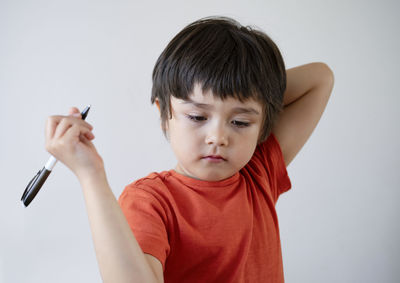 Boy holding pen over gray background