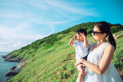 Young woman drinking water while standing against sea against sky