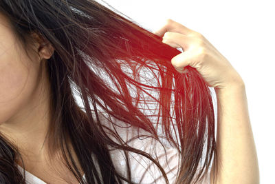 Cropped image of woman with hand tangled hair against white background