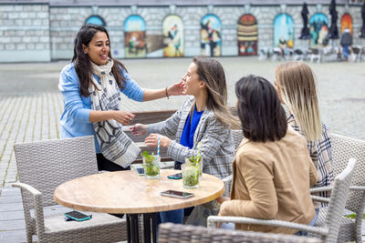 Side view of friends sitting on table