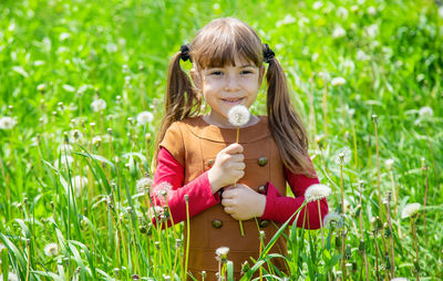 Portrait of smiling girl holding dandelion seed