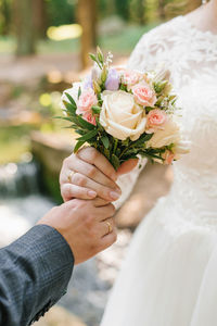 The groom holds out a wedding bouquet to the bride. close-up of newlywed hands and delicate bouquet