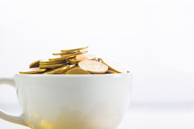 Close-up of fresh bread in bowl on table against white background