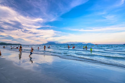 People enjoying at beach against sky