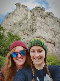 Portrait of smiling young woman wearing sunglasses against mountain