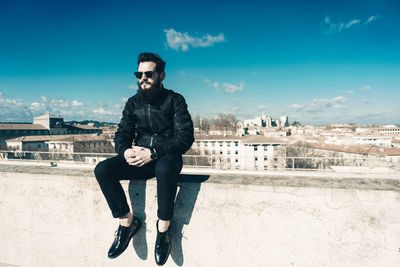 Portrait of young man sitting against built structure