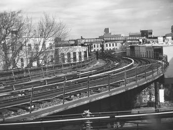 Bridge in city against cloudy sky